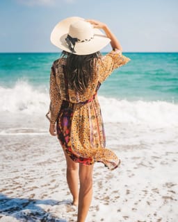Woman walking along the beach at sunset with waves lapping the shore