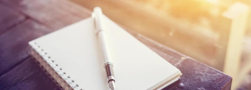 Person writing in a notebook with a pen, journaling and reflecting
